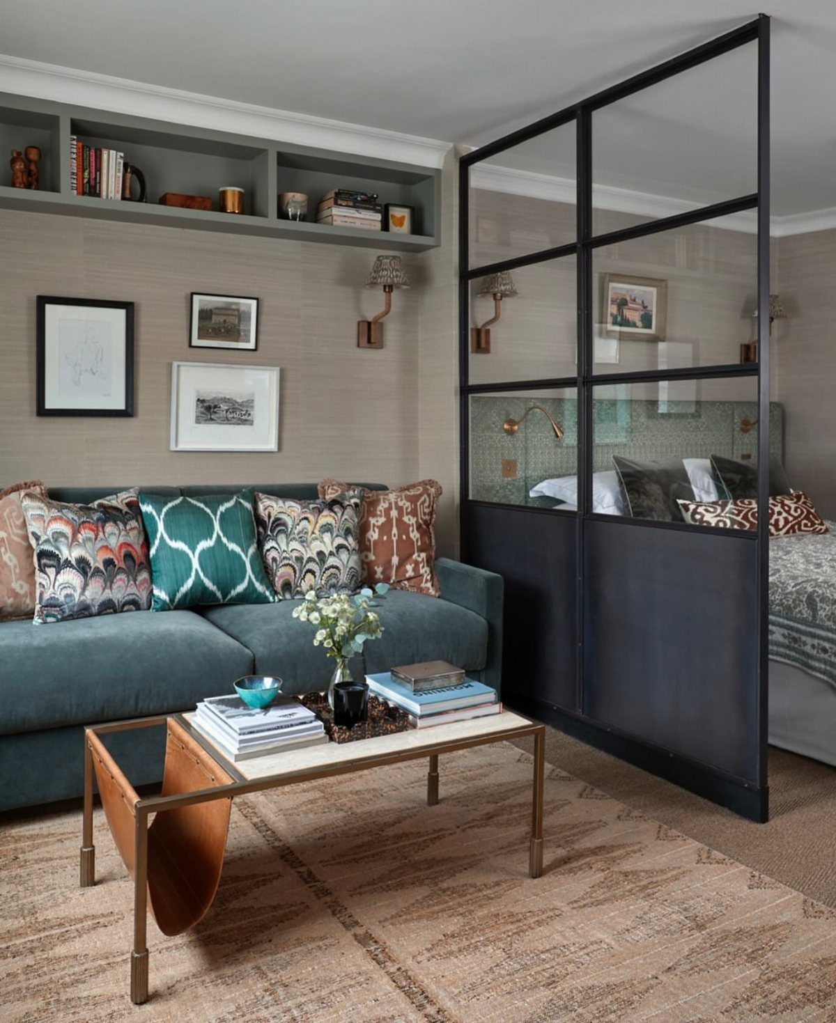 Teal sofa and gold coffee table in a studio with glass room divider.