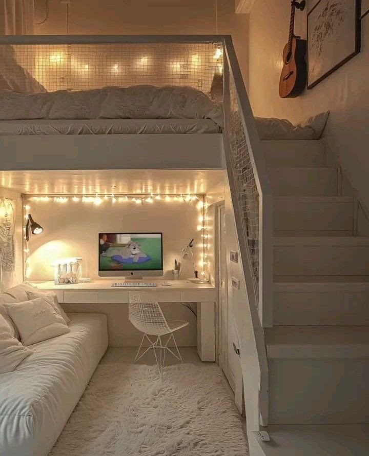 Loft bed with stairs over a desk and sofa in a white room.