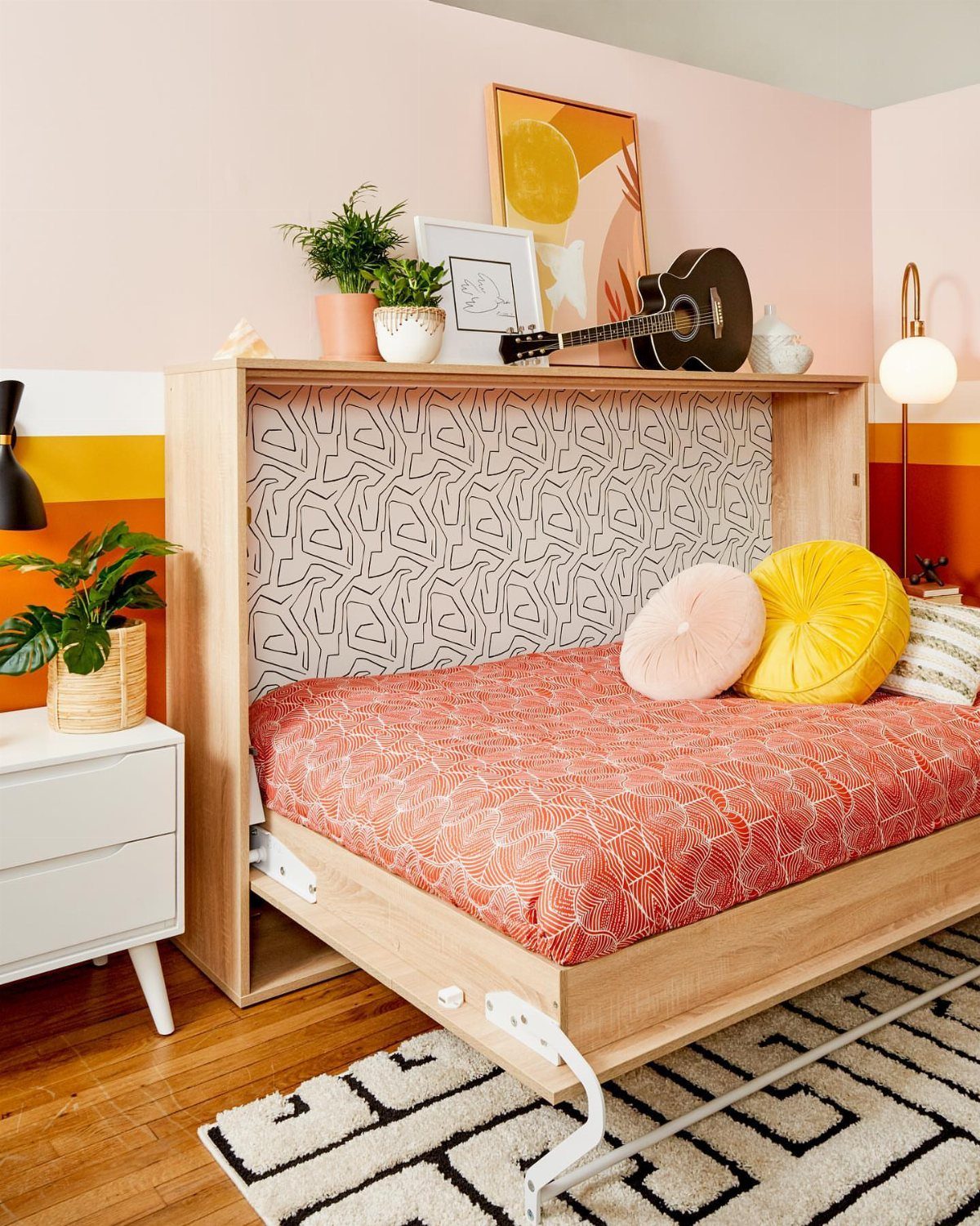 Murphy bed with red bedding and light wood frame in a colorful room
