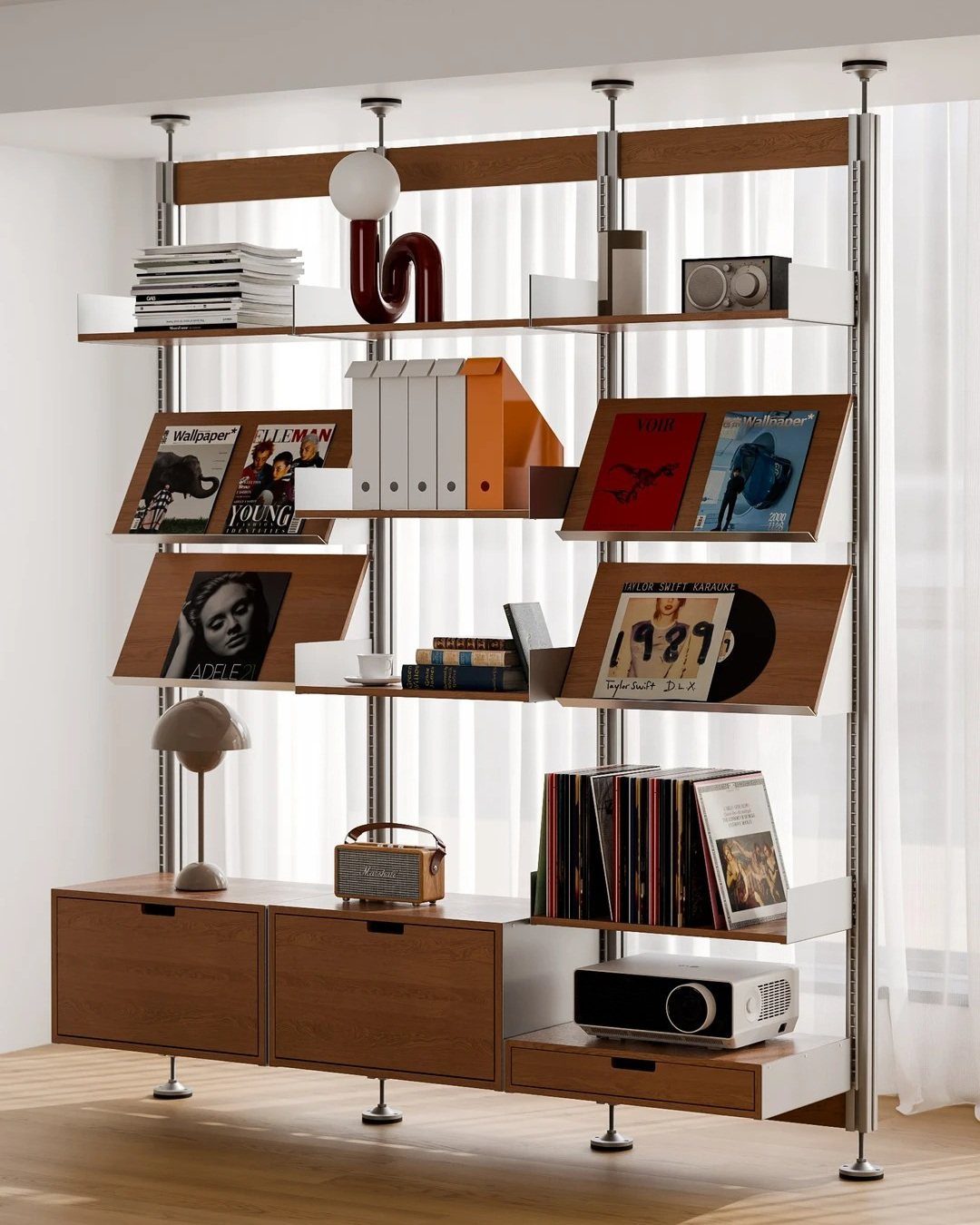 Modular wooden open shelving unit holding books and electronics against white curtains.