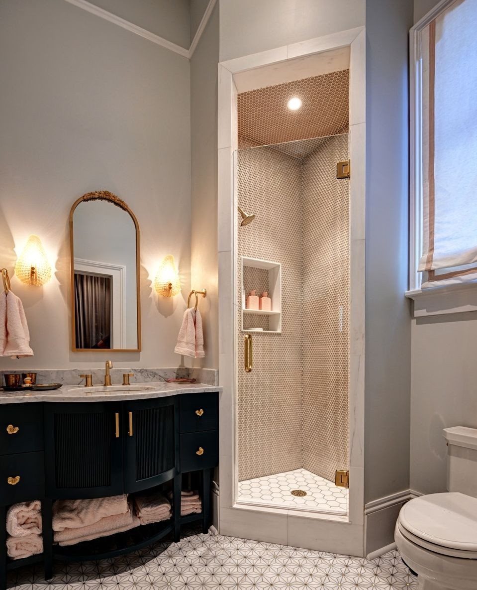 Corner walk-in shower with beige mosaic tiles next to a dark blue vanity.