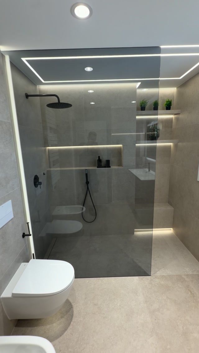 Modern walk-in shower with matte black fixtures, grey tiles, and integrated LED lighting.
