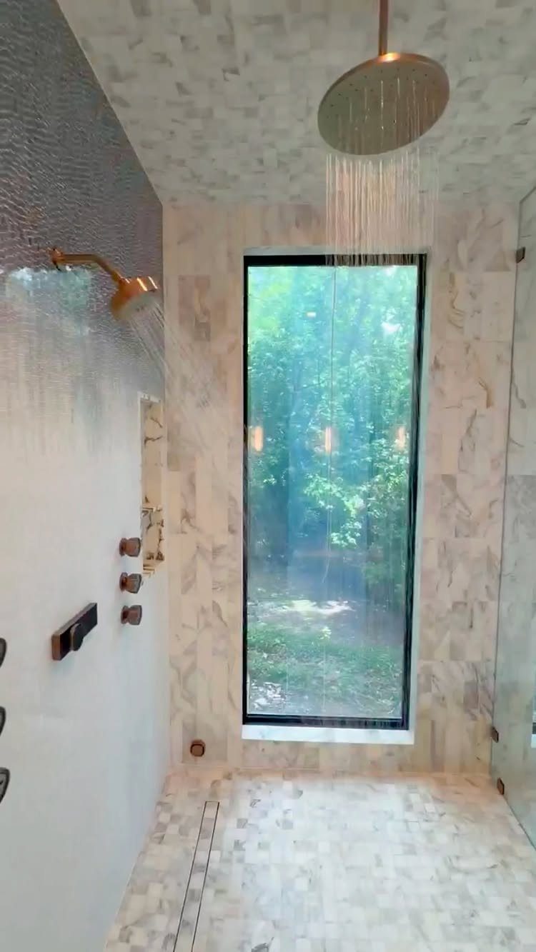 Walk-in shower with gold rain showerhead and wall-mounted showerhead spraying water
