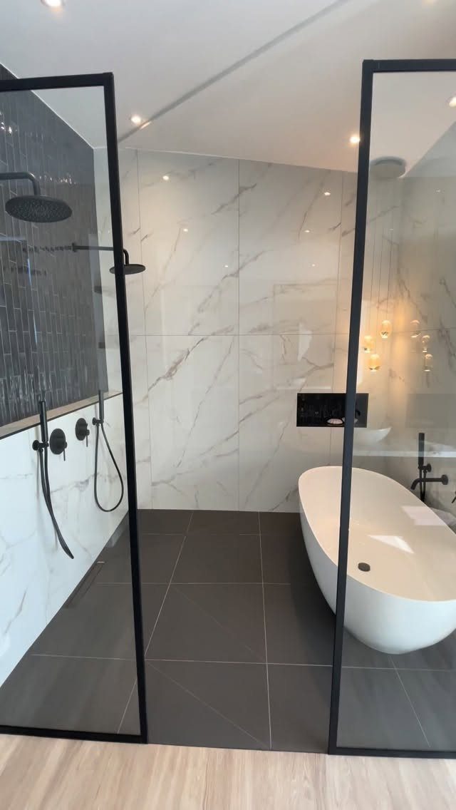 Modern wet room with a freestanding white tub and black-framed glass shower enclosure.