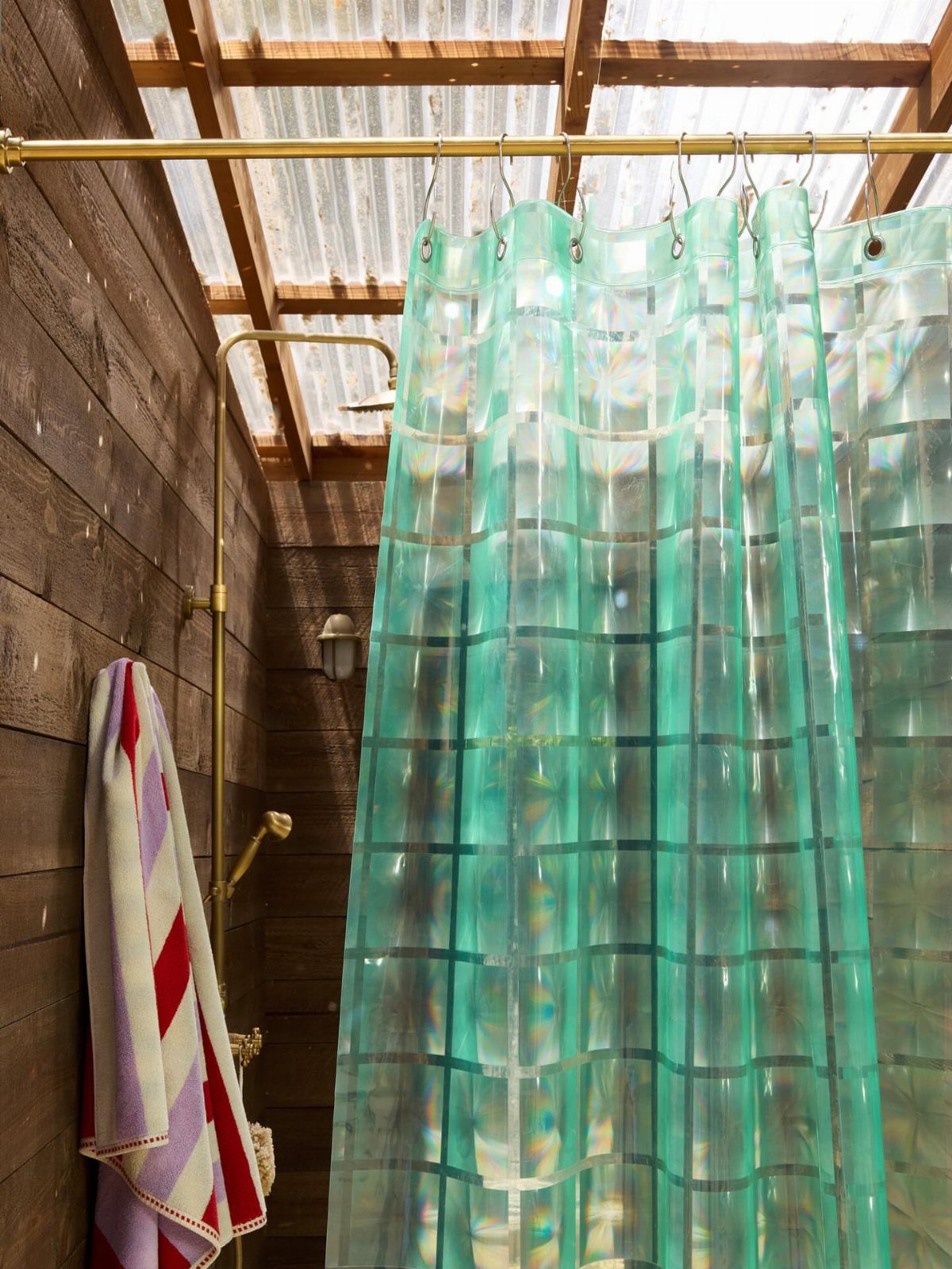 Green translucent shower curtain hanging in a rustic wooden walk-in shower area.