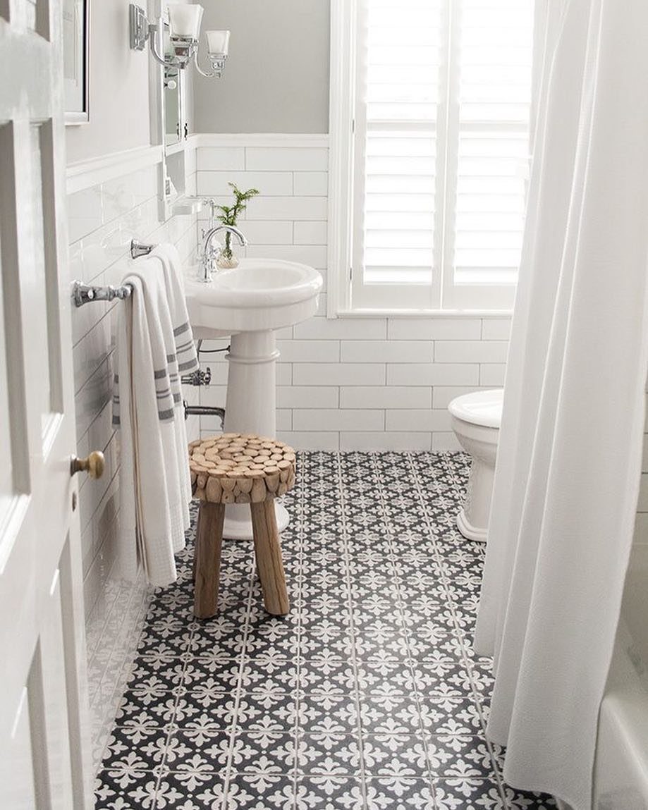 Black and white patterned encaustic floor tiles in a bright white bathroom