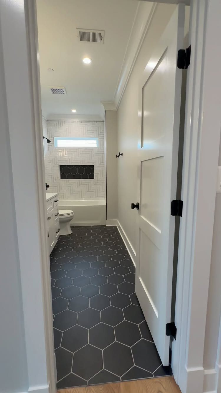Bathroom with dark grey hexagonal floor tiles and white subway wall tiles.