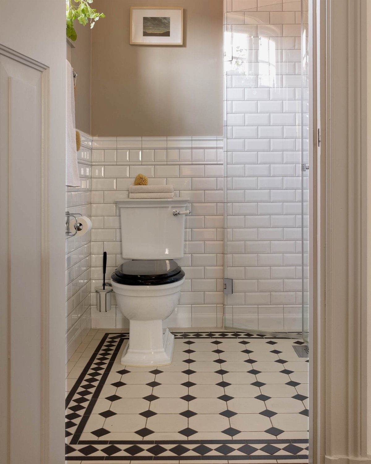 White bathroom with subway wall tiles and black and white diamond floor tiles.