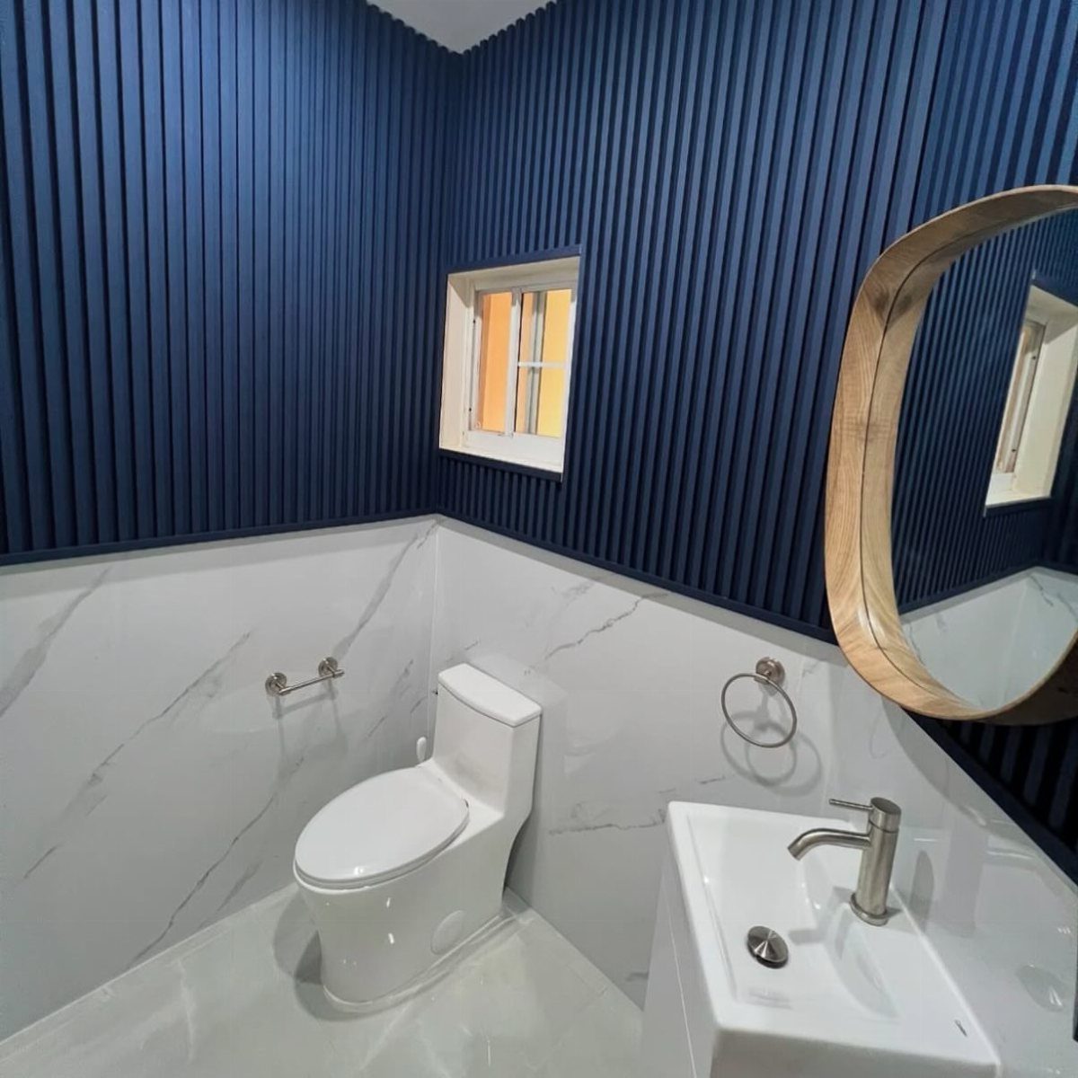 Navy blue slatted accent walls above white marble tiling in a modern bathroom.