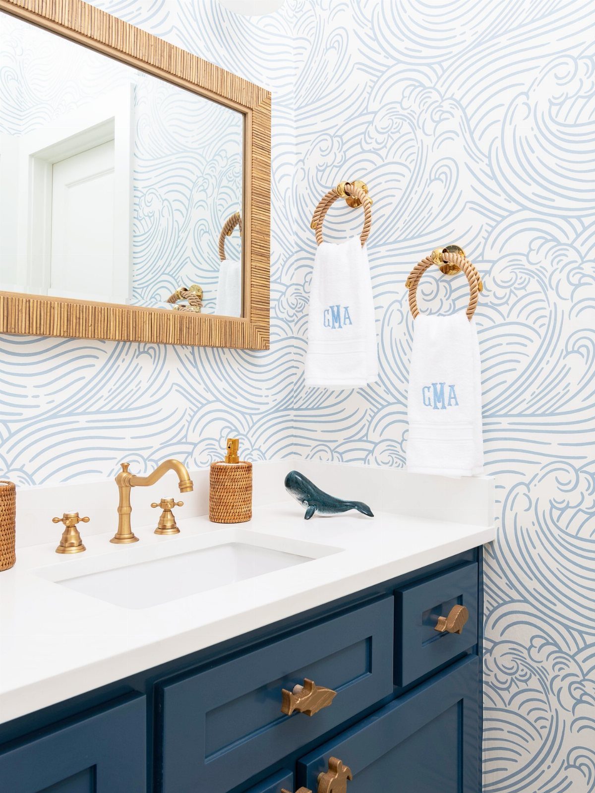 Navy blue vanity with white countertop against blue and white wave patterned wallpaper.